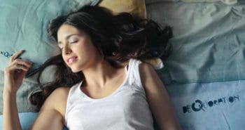 photo of woman in white tank top lying on bed